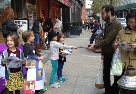 Kids hand out fliers on the sidewalk to support their supply drive.