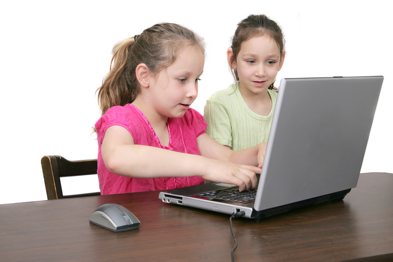 Two girls use a laptop together.