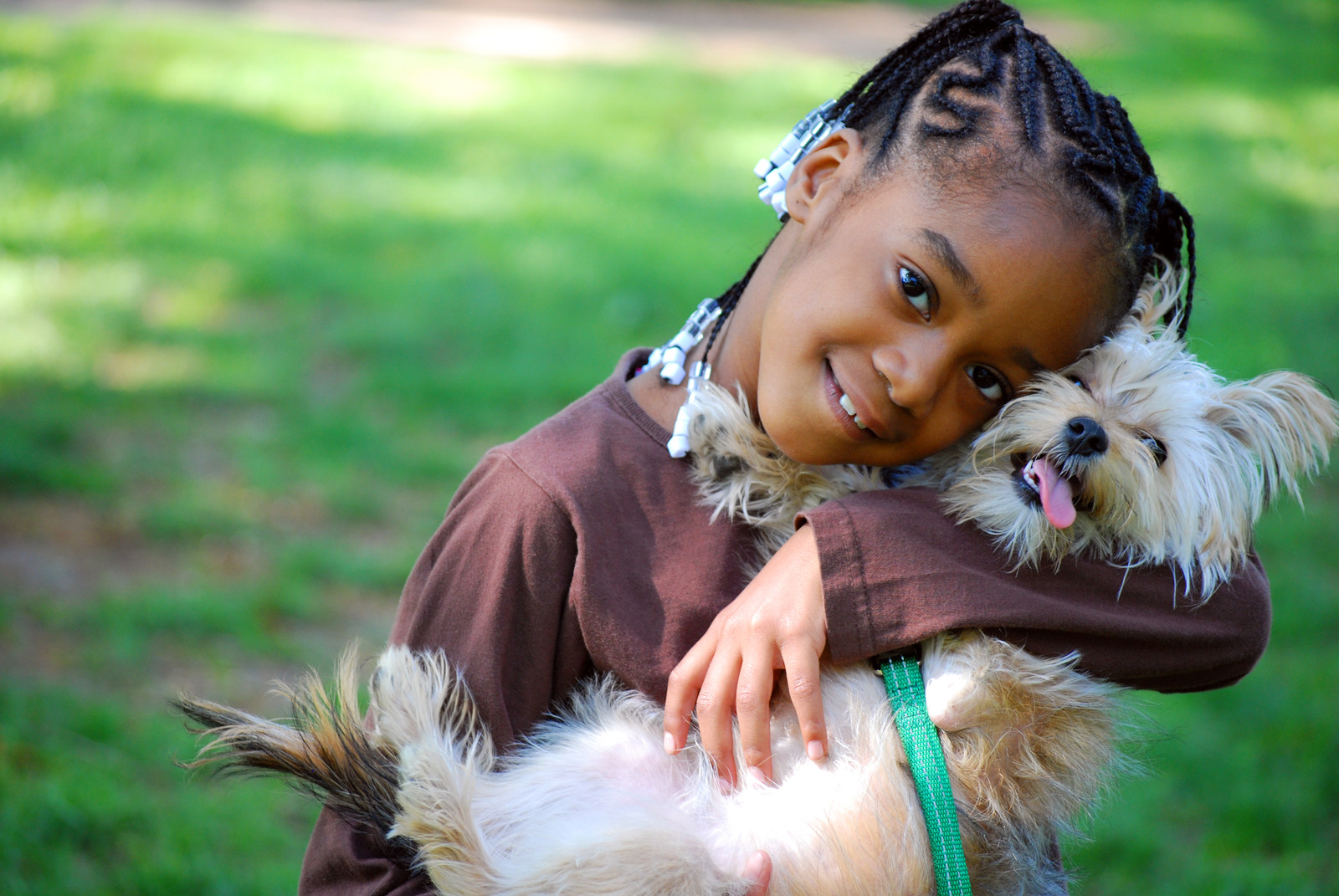 A young girl cradles and nuzzles a Yorkshire Terrier.